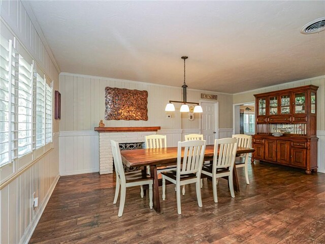 dining room with ornamental molding, dark wood-type flooring, and a brick fireplace