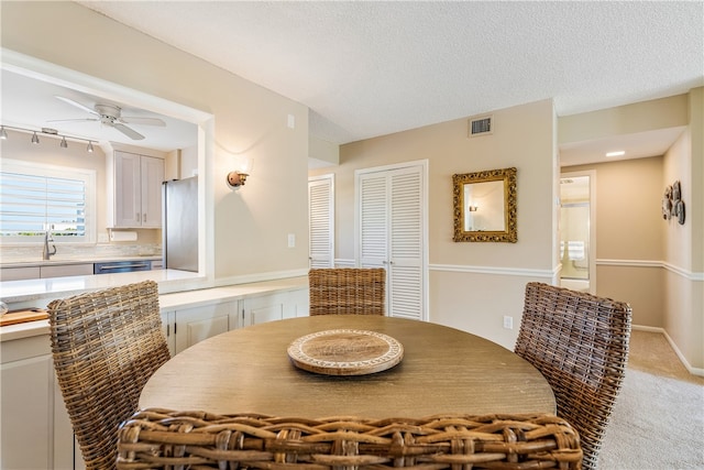 carpeted dining room featuring sink, a textured ceiling, and ceiling fan