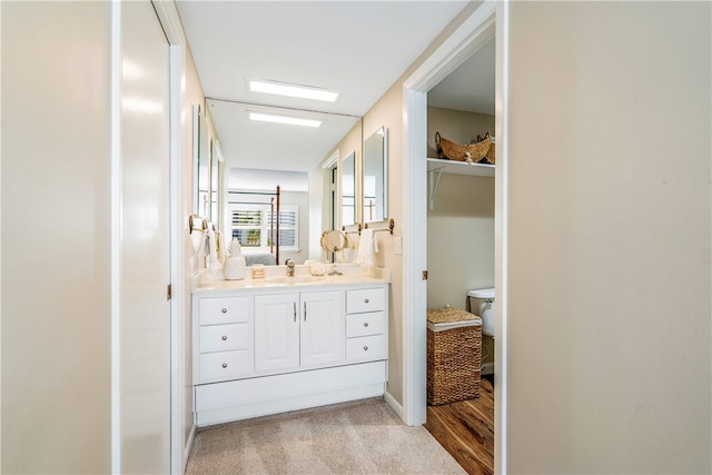 bathroom with hardwood / wood-style floors, vanity, and toilet