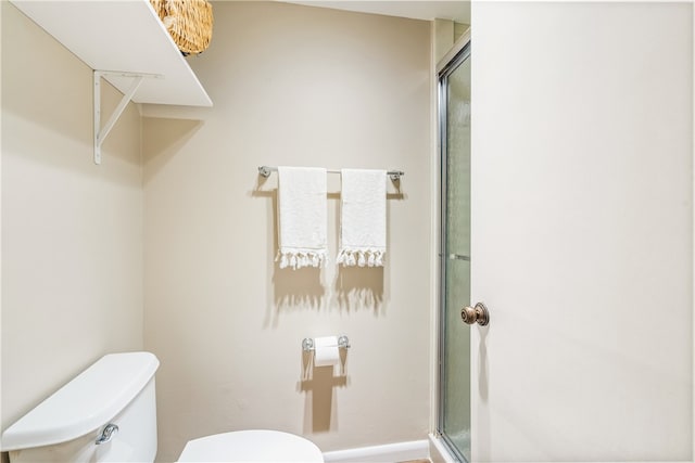 bathroom featuring toilet and a shower with door