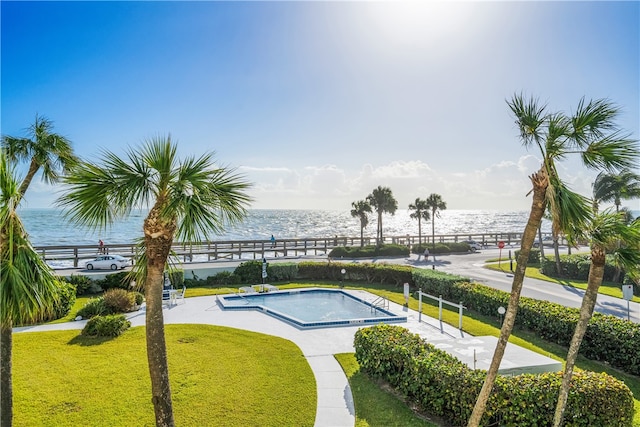 view of pool featuring a water view and a yard