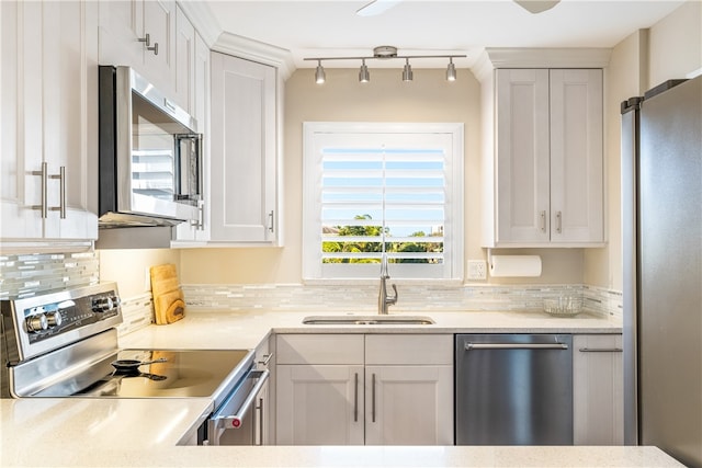 kitchen featuring stainless steel appliances, sink, tasteful backsplash, rail lighting, and white cabinets