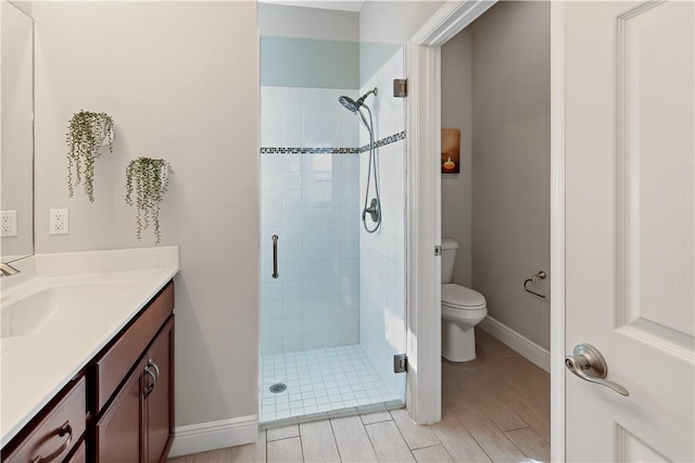 full bath featuring a stall shower, toilet, vanity, and baseboards