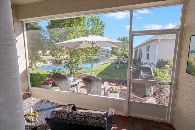 interior space featuring a textured wall, a sunroom, brick floor, and a water view