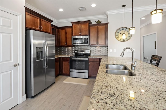 kitchen with light stone counters, light wood-style flooring, a sink, stainless steel appliances, and backsplash