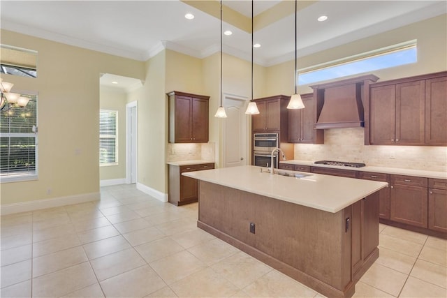 kitchen with decorative light fixtures, an island with sink, sink, crown molding, and wall chimney exhaust hood