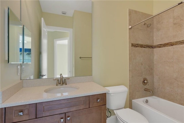 full bathroom with tiled shower / bath, vanity, and toilet