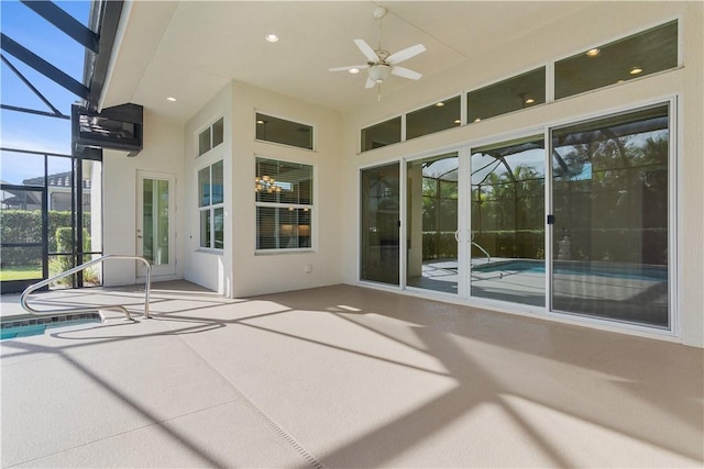 view of patio featuring ceiling fan and glass enclosure