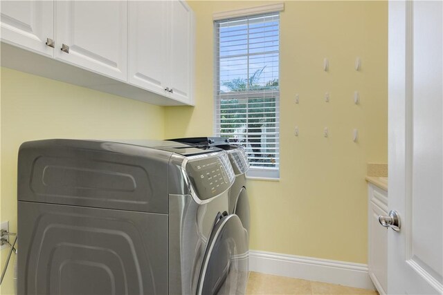 washroom featuring independent washer and dryer, light tile patterned floors, and cabinets