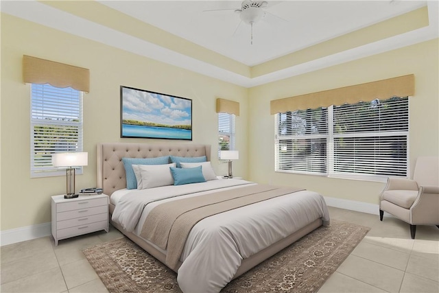 tiled bedroom with a raised ceiling and ceiling fan