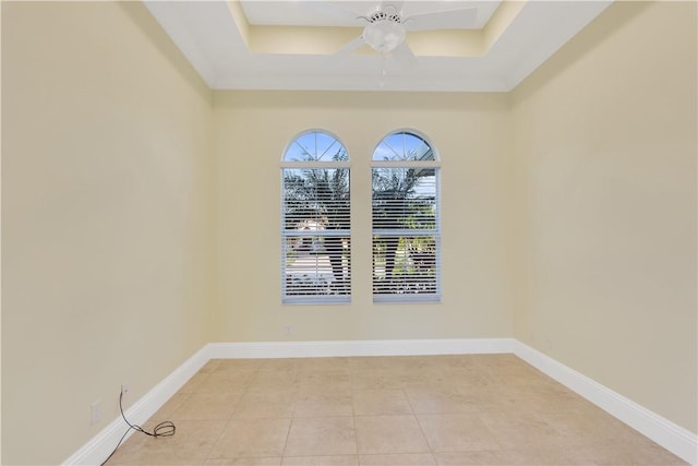 spare room with light tile patterned floors, a raised ceiling, and ceiling fan