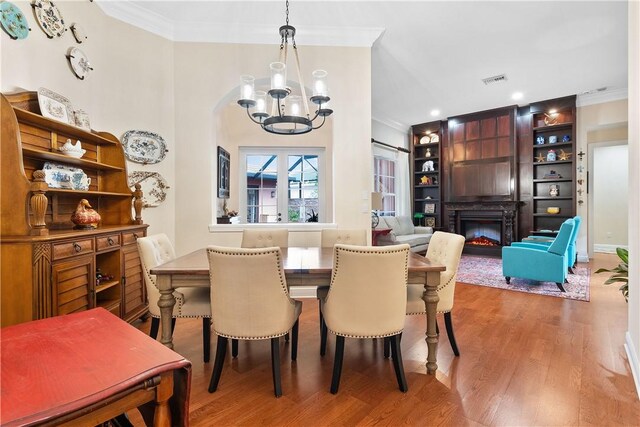 1155 Governors Way, Vero Beach, FL 32963 - dining room featuring crown molding, a chandelier, wood finished floors, and a lit fireplace