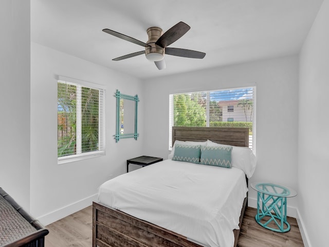 bedroom with ceiling fan, multiple windows, and light wood-type flooring