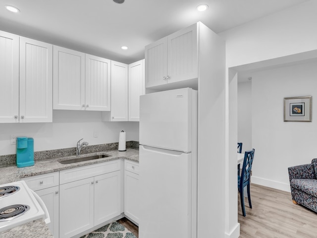 kitchen with white cabinetry, light stone countertops, sink, white appliances, and light hardwood / wood-style flooring