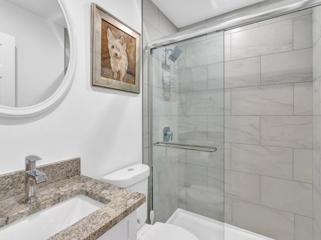 bathroom with vanity, toilet, and a shower with door