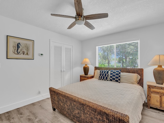 bedroom featuring a closet, light wood-type flooring, a textured ceiling, and ceiling fan