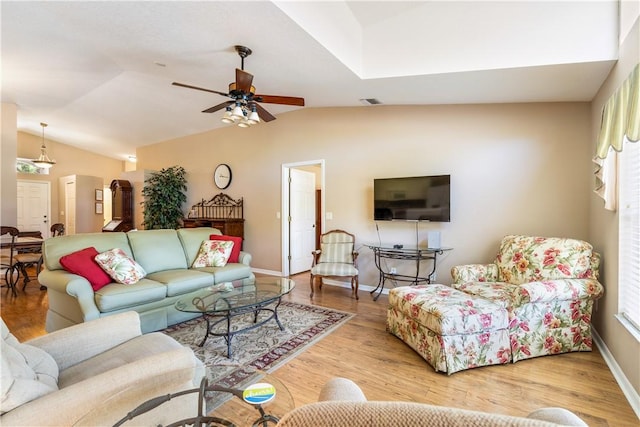 living area featuring vaulted ceiling, baseboards, a ceiling fan, and wood finished floors