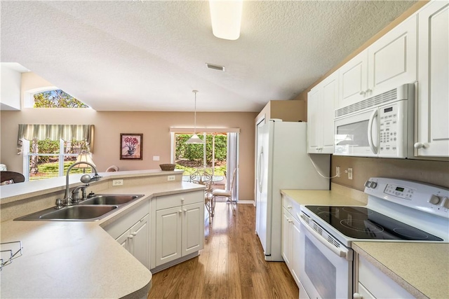 kitchen with light wood finished floors, visible vents, light countertops, white appliances, and a sink