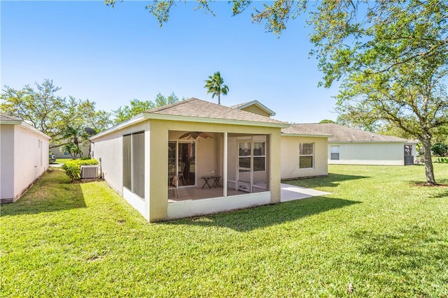 back of property featuring stucco siding, a lawn, central AC, roof with shingles, and a sunroom