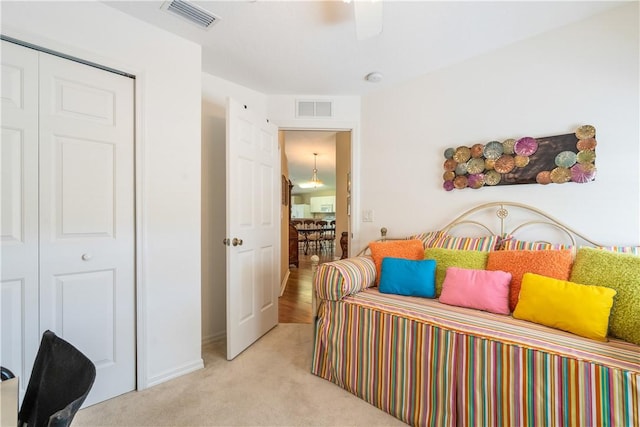 bedroom featuring light carpet, visible vents, ceiling fan, and a closet