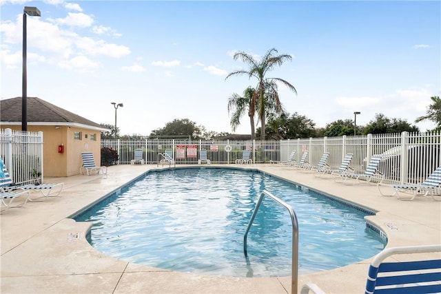 pool with a patio area and fence