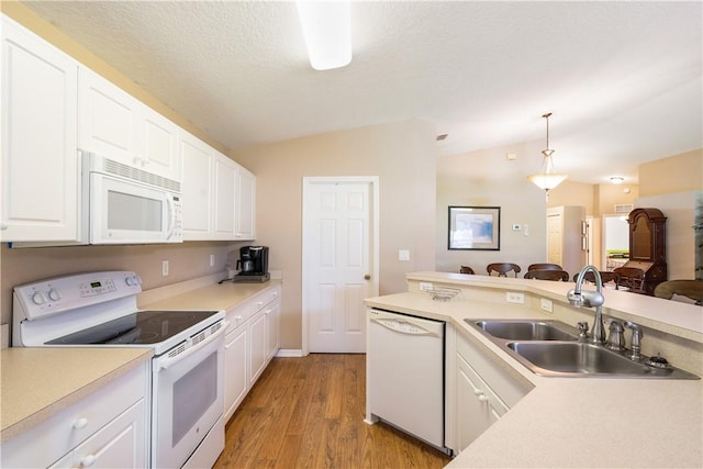 kitchen with white appliances, lofted ceiling, light wood-style flooring, a sink, and light countertops