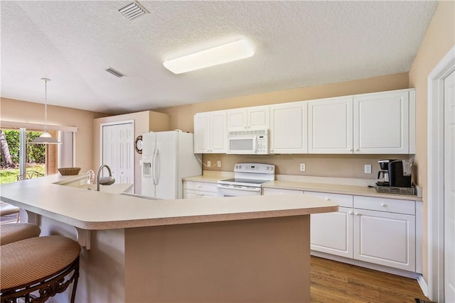 kitchen with a kitchen breakfast bar, white appliances, white cabinetry, and light countertops