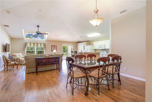 dining space with light wood-type flooring, visible vents, baseboards, and ceiling fan