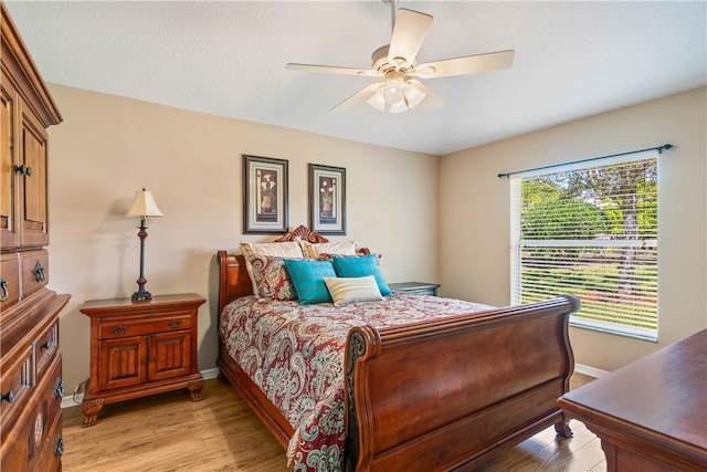 bedroom with light wood-type flooring, baseboards, and ceiling fan