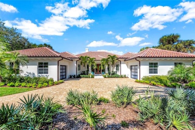 view of front of home with a garage, decorative driveway, a tile roof, and stucco siding