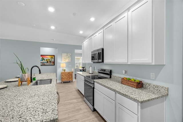 8645 95th Ave, Vero Beach, FL 32967 - kitchen with stainless steel appliances, a sink, white cabinets, light wood finished floors, and recessed lighting