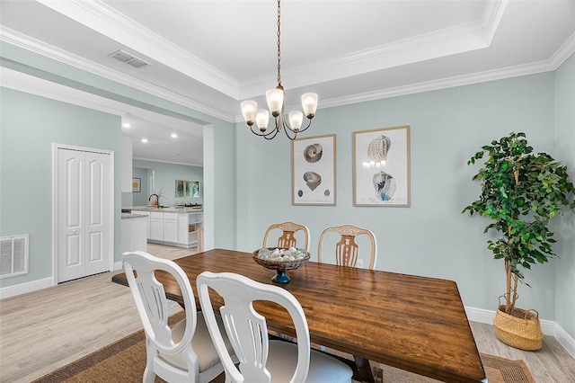 8645 95th Ave, Vero Beach, FL 32967 - dining space with light wood-type flooring, a chandelier, crown molding, baseboards, and a tray ceiling