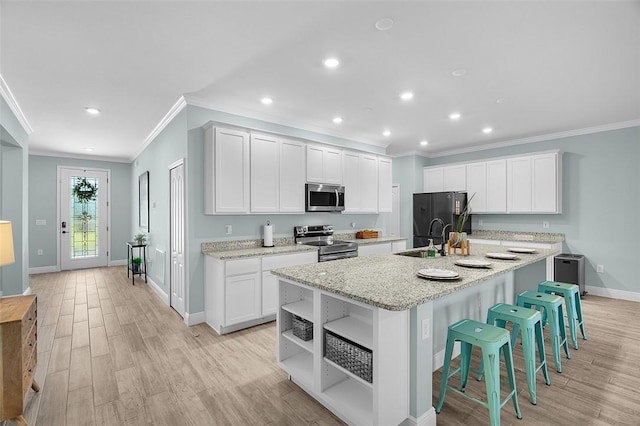 8645 95th Ave, Vero Beach, FL 32967 - kitchen with stainless steel appliances, crown molding, baseboards, a sink, and light wood-style floors