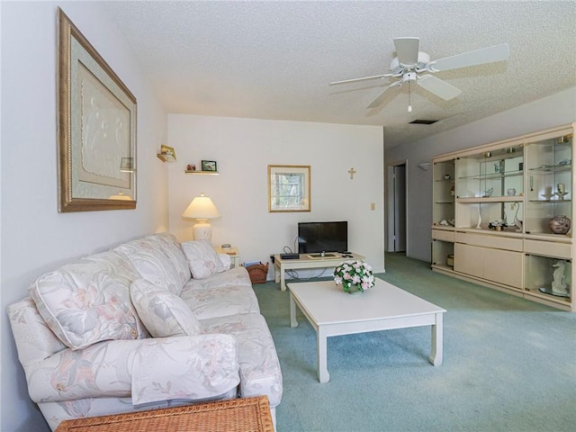 living room with ceiling fan, light colored carpet, and a textured ceiling