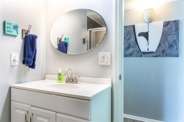 bathroom featuring a shower with door and vanity