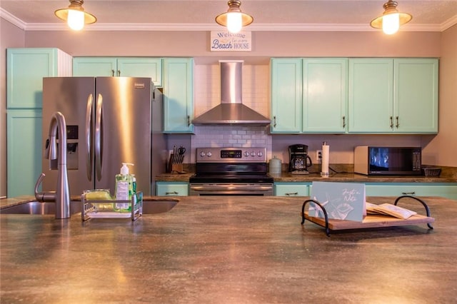 kitchen featuring appliances with stainless steel finishes, backsplash, ornamental molding, green cabinetry, and wall chimney range hood