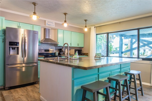 kitchen with pendant lighting, stainless steel appliances, light hardwood / wood-style floors, and wall chimney exhaust hood