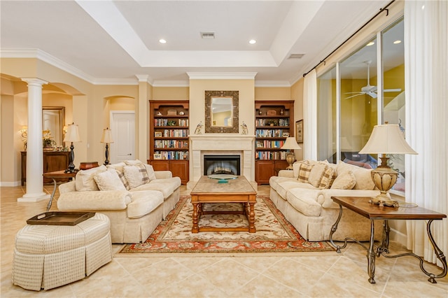 tiled living room featuring ceiling fan, a raised ceiling, ornamental molding, and decorative columns