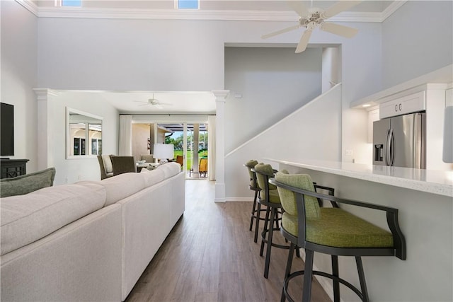 living room featuring dark hardwood / wood-style flooring, ornamental molding, ceiling fan, and ornate columns