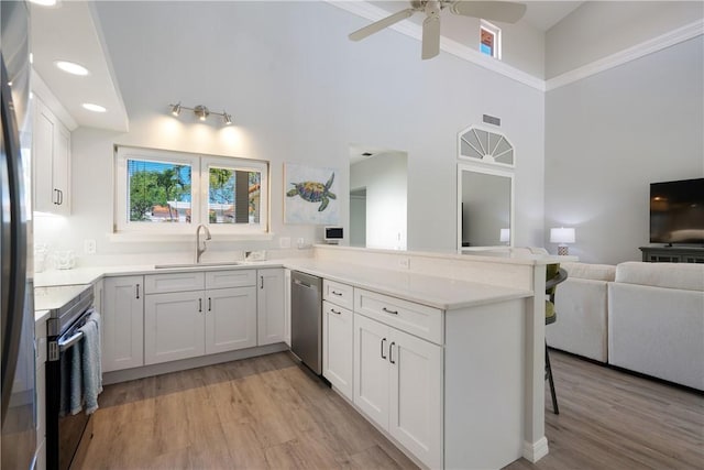 kitchen with white cabinetry, sink, range, stainless steel dishwasher, and kitchen peninsula