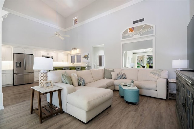 living room featuring a high ceiling, wood-type flooring, and ceiling fan