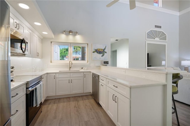 kitchen featuring appliances with stainless steel finishes, a kitchen bar, kitchen peninsula, and white cabinets