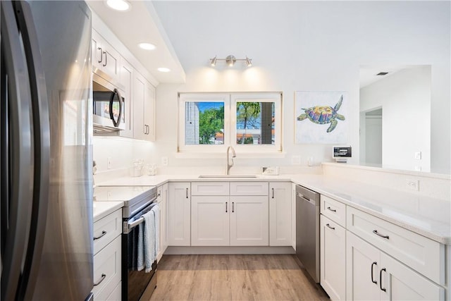 kitchen featuring sink, light wood-type flooring, white cabinets, and appliances with stainless steel finishes