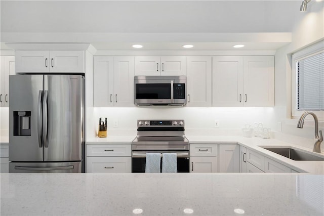 kitchen featuring white cabinetry, sink, light stone counters, and stainless steel appliances