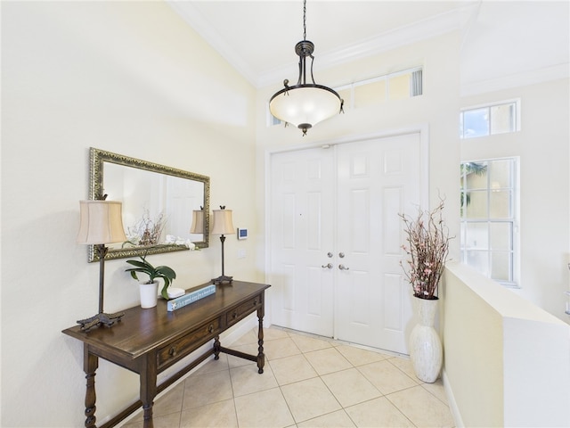 foyer with light tile patterned floors, baseboards, a towering ceiling, and ornamental molding