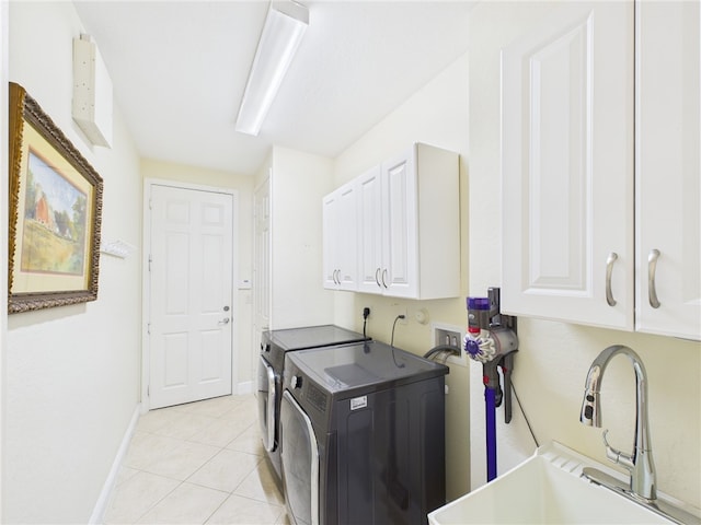 washroom with a sink, cabinet space, light tile patterned flooring, baseboards, and washing machine and clothes dryer