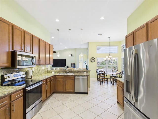 kitchen featuring an inviting chandelier, a sink, stainless steel appliances, pendant lighting, and backsplash