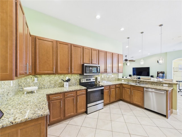 kitchen with brown cabinets, a sink, tasteful backsplash, appliances with stainless steel finishes, and a peninsula