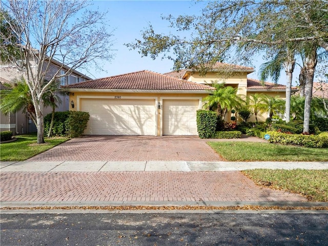 view of front of property with decorative driveway, a tile roof, an attached garage, and stucco siding