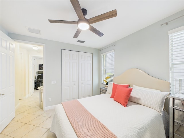 bedroom featuring baseboards, visible vents, light tile patterned flooring, ceiling fan, and a closet